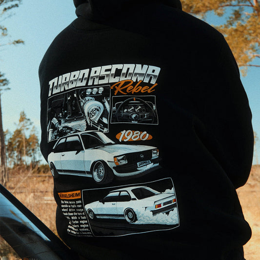 Person wearing a black hoodie with car-themed graphics and text outdoors.